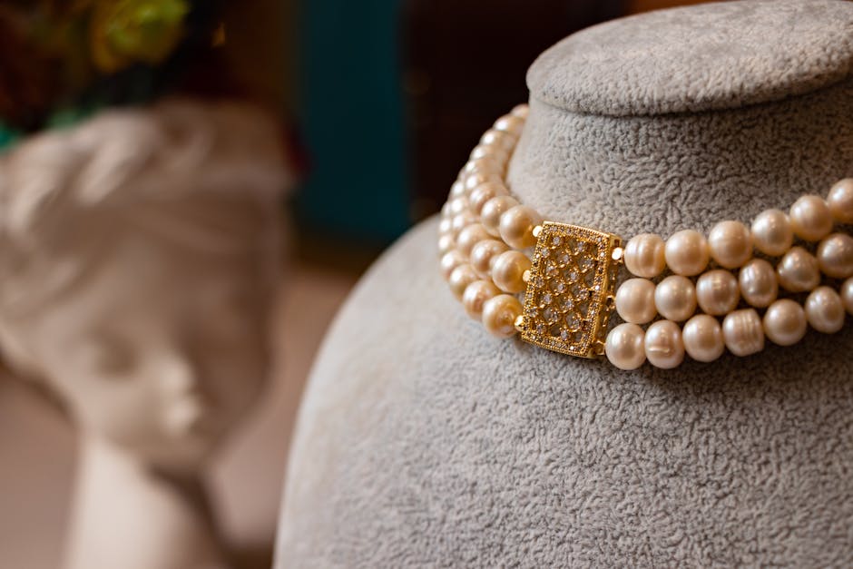 Close-up of a luxurious pearl necklace with a golden clasp on a display bust.