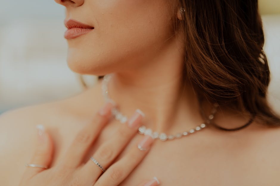 Close-up of a woman touching her diamond necklace with manicured nails.