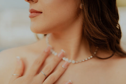 Close-up of a woman touching her diamond necklace with manicured nails.